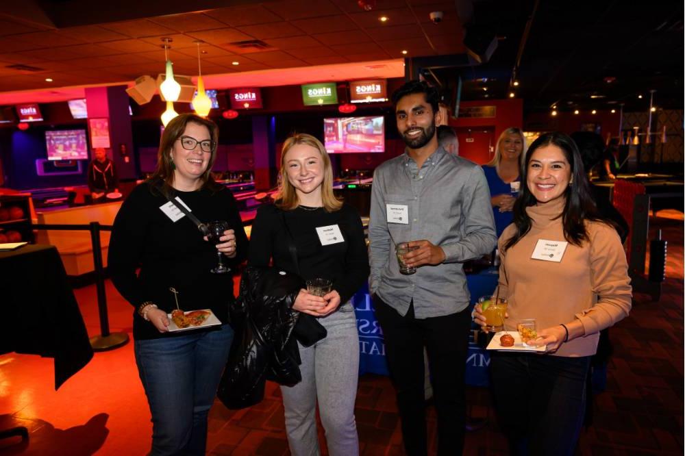 Four alumni with food and drinks at the event together.